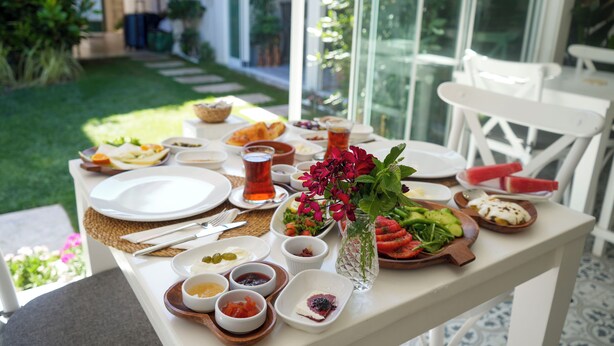 Ein Tisch ist für eine Mahlzeit gedeckt, mit verschiedenen Gerichten, einem Teeglas und einer Vase mit Blumen.