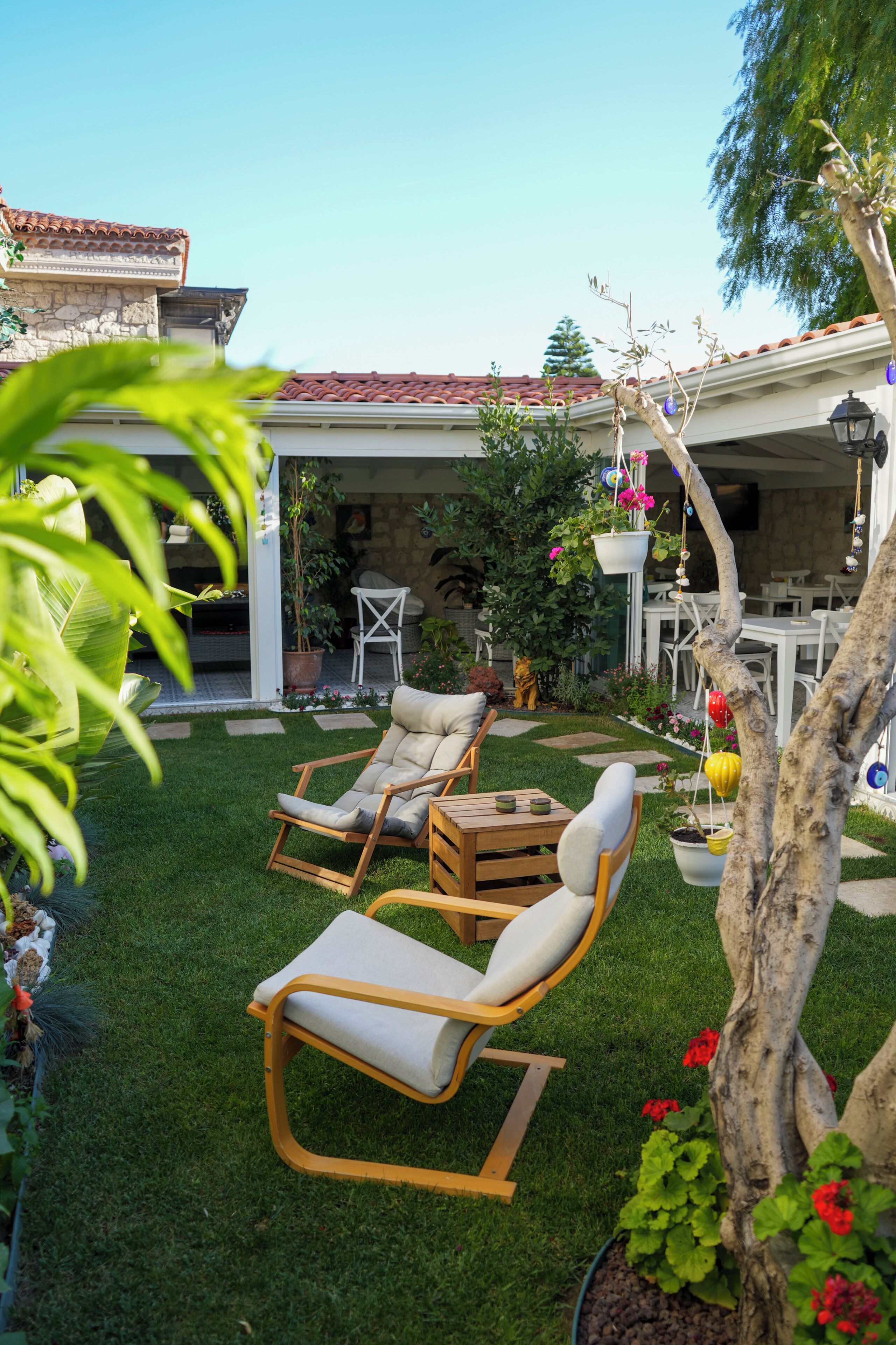 Un patio con dos sillones de descanso, una mesita y una planta en maceta.