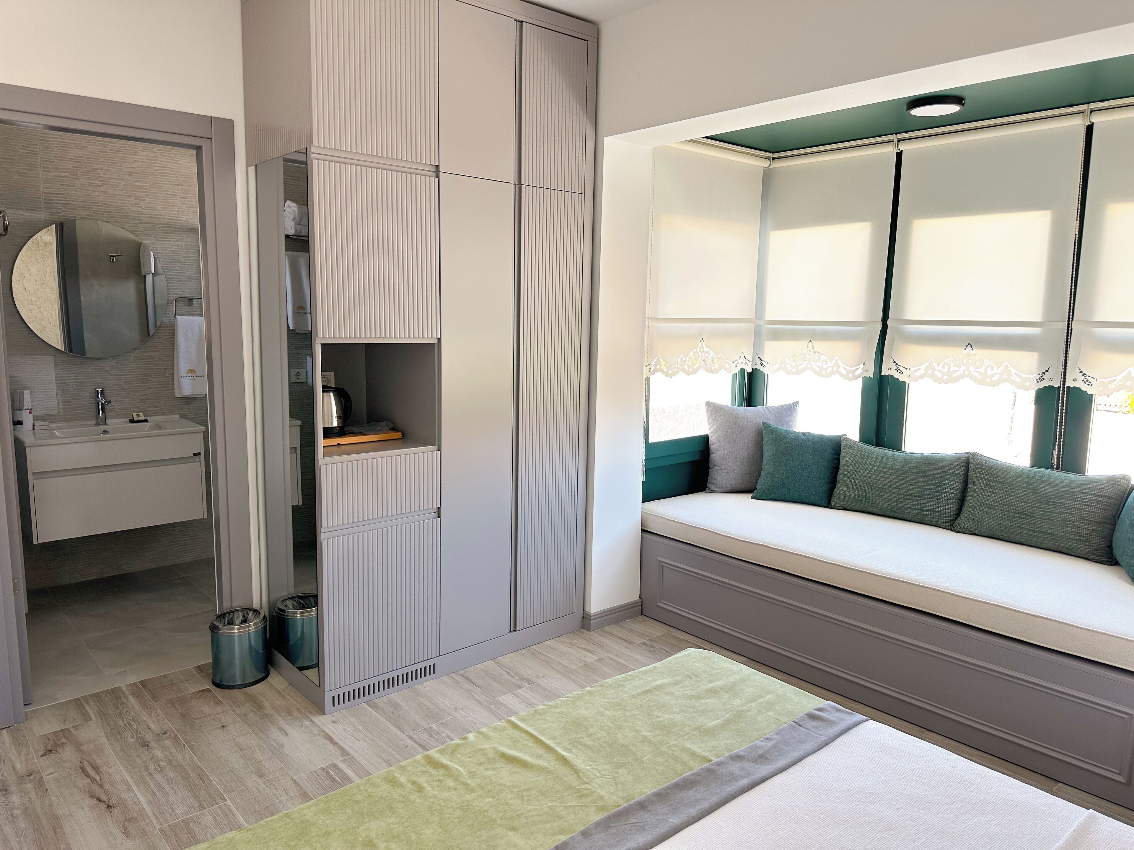 Un dormitorio moderno con un asiento incorporado junto a la ventana, un espejo grande y un armario con puertas correderas.