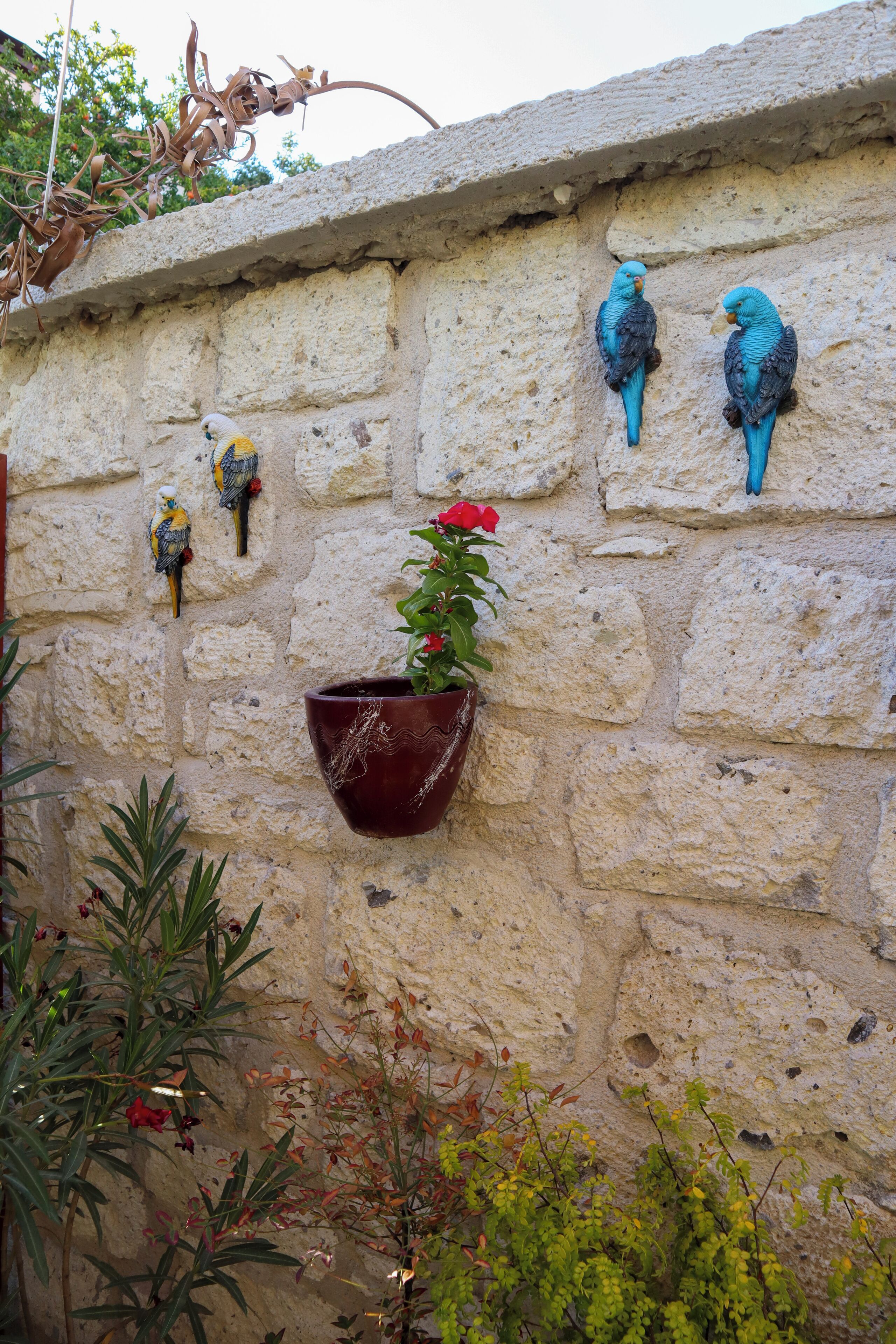 Un mur de pierre orné de sculptures d’oiseaux et d’une plante en pot.