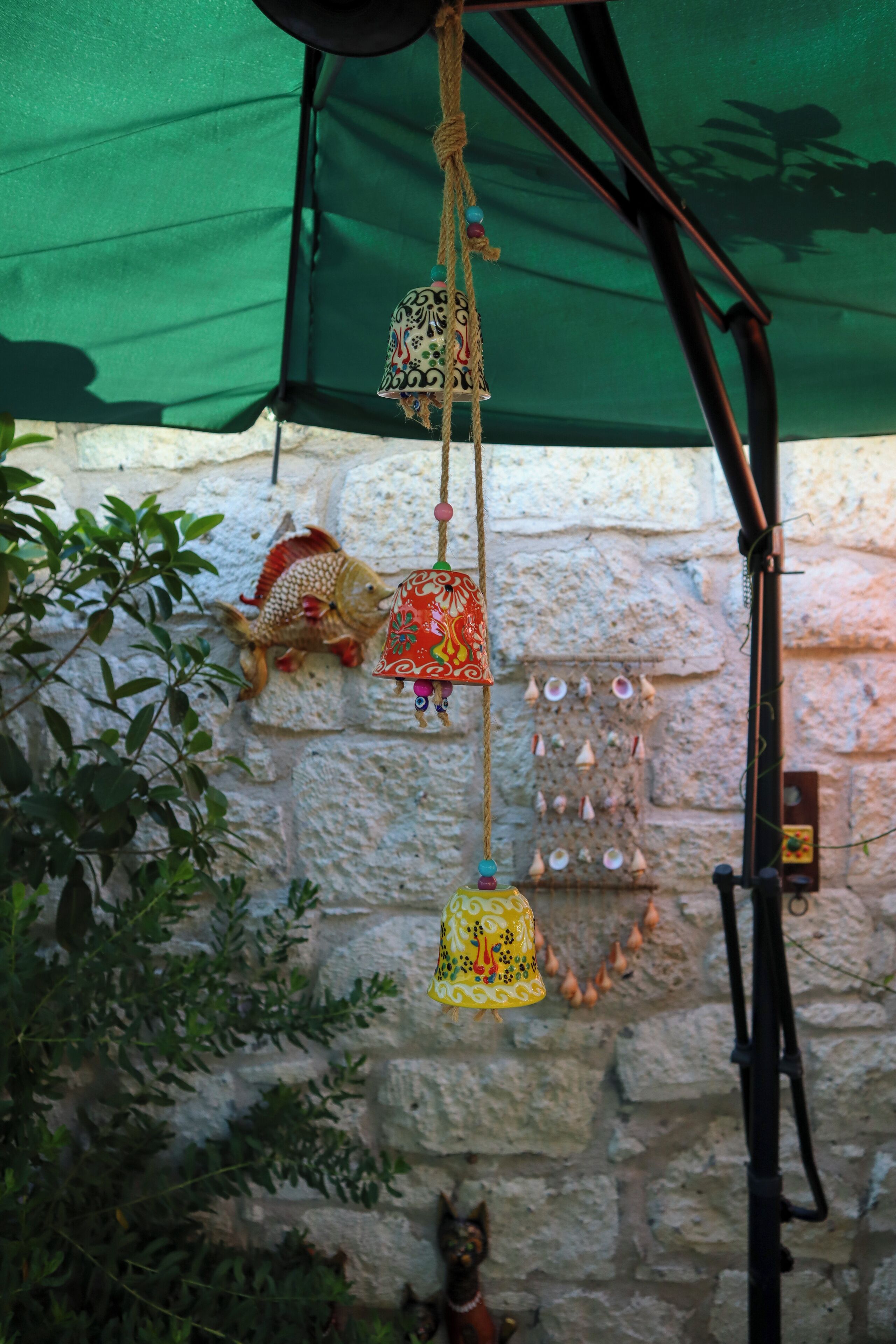 A stone wall with decorative elements including a fish, hanging bells, and a small figurine.