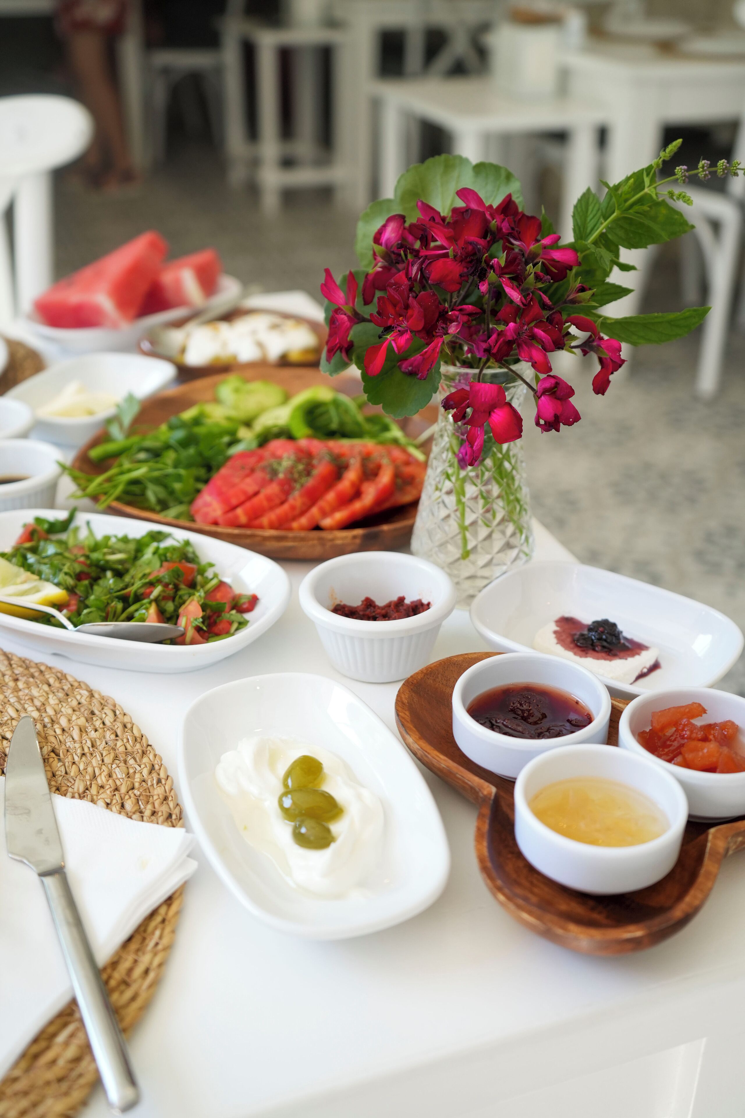 Una mesa con diversos alimentos, entre ellos ensaladas, frutas y salsas.