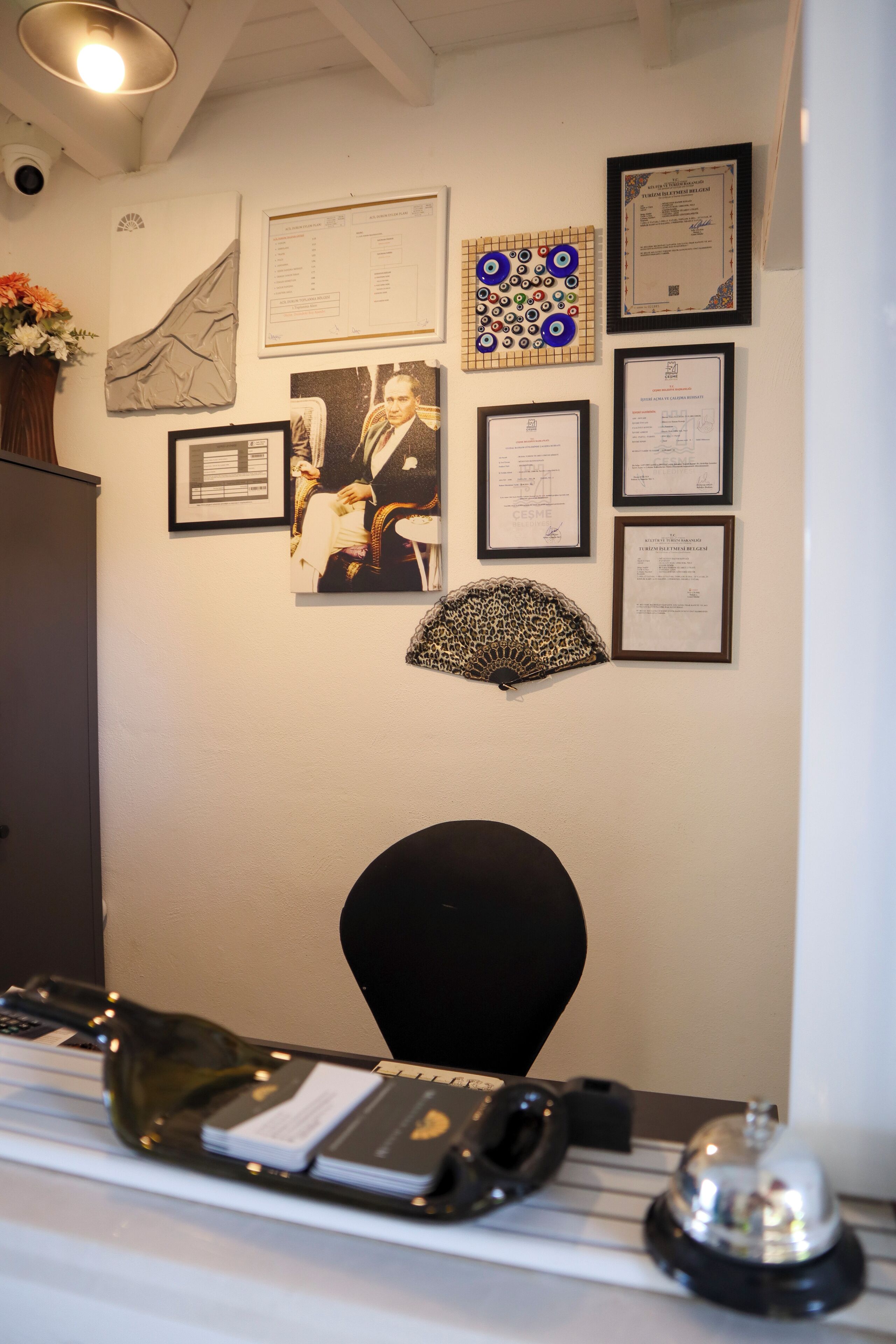 A reception desk with framed certificates, a fan, and a vase of flowers.