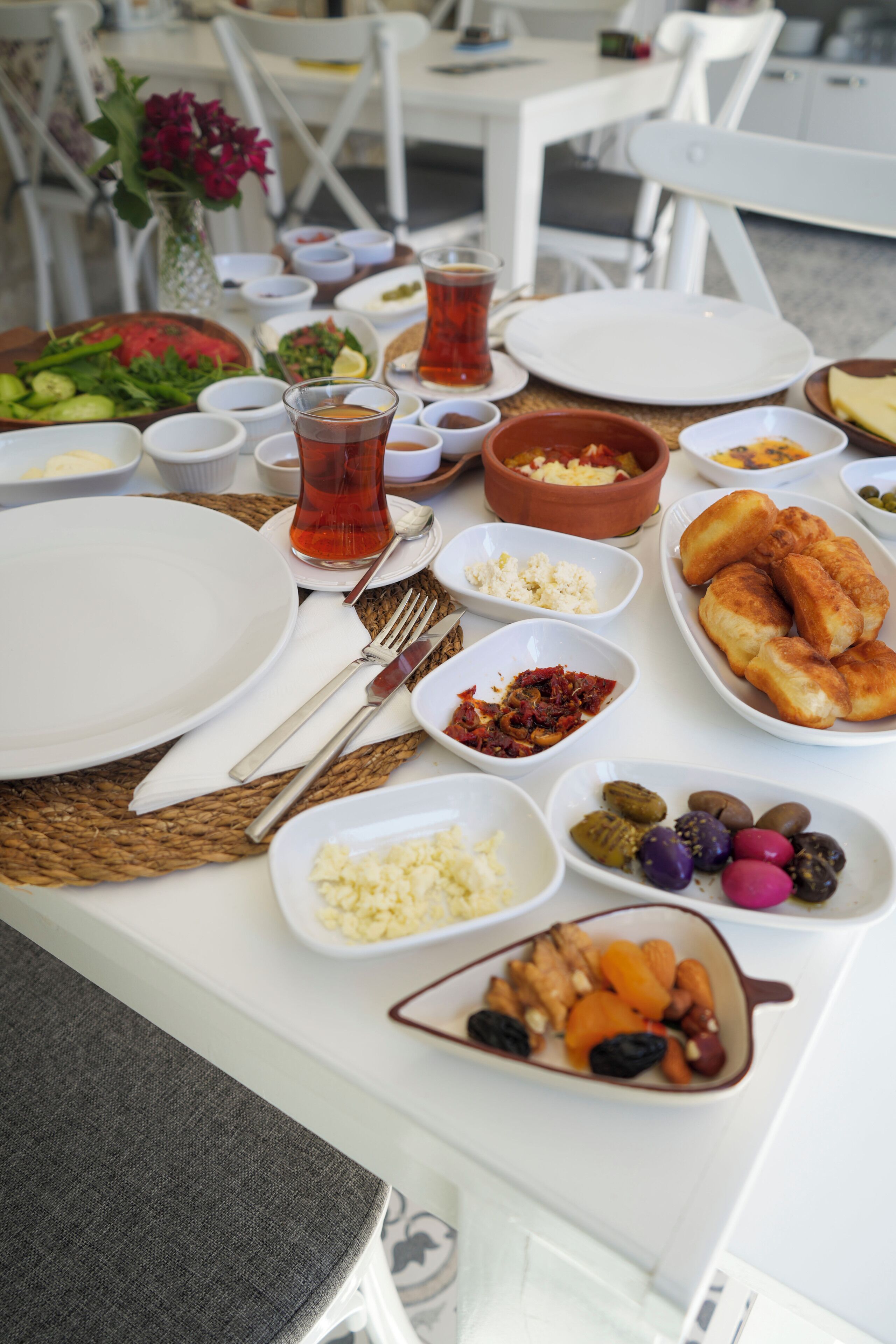 A table set with various dishes, including bread, vegetables, and a glass of tea.