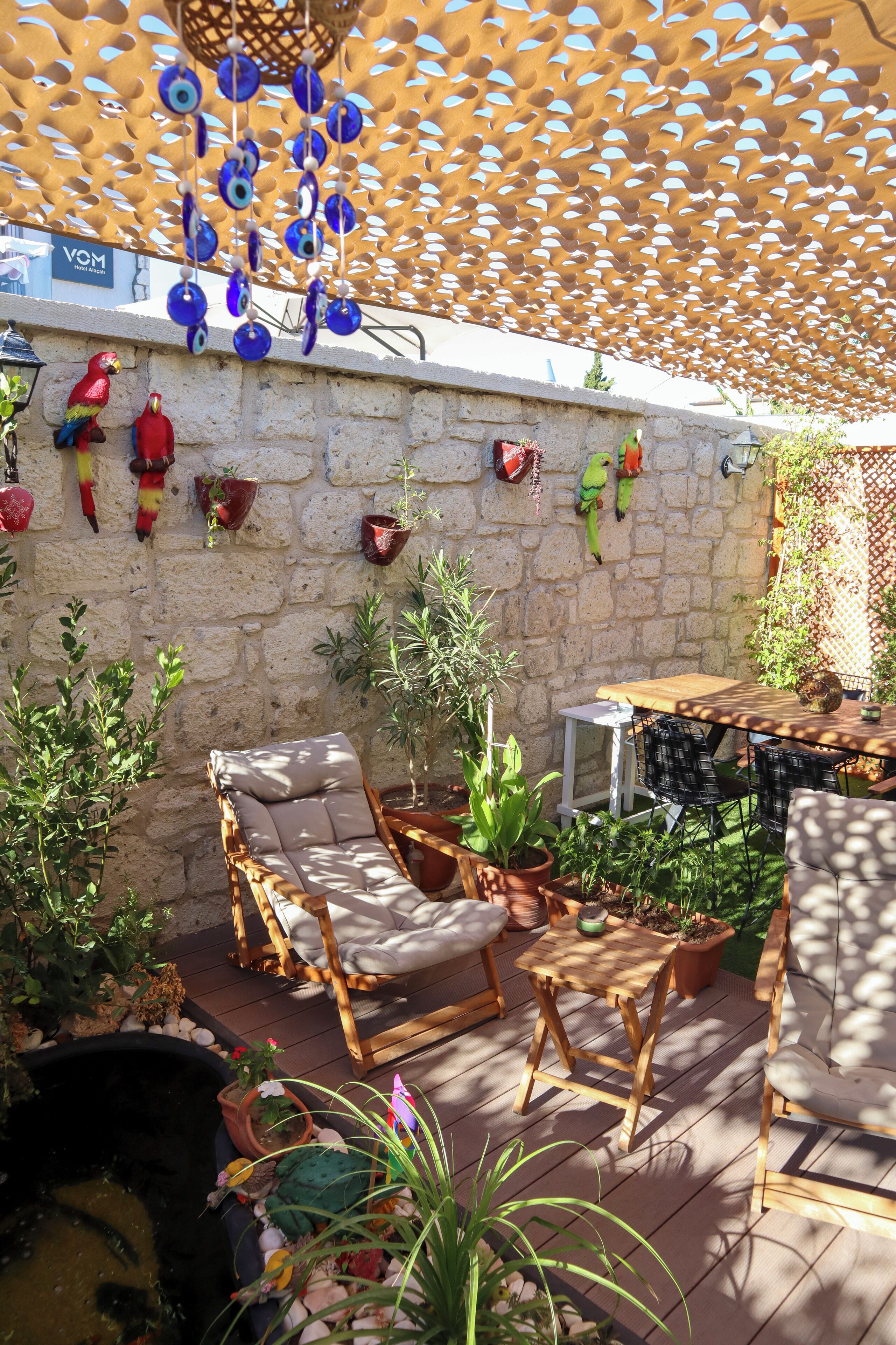 A patio with wicker furniture, potted plants, and decorative wall hangings.