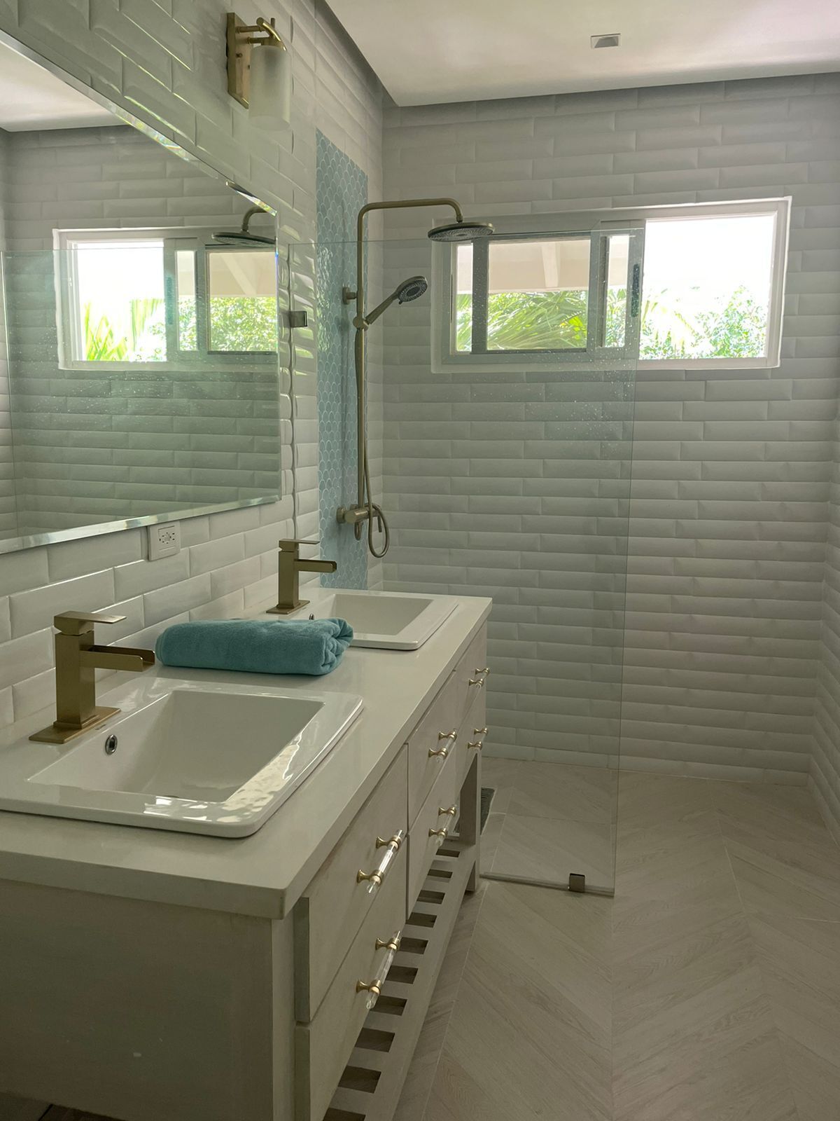 Un baño moderno con dos lavamanos, ducha y ventana.