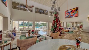 Ein geräumiges Wohnzimmer mit einem großen Weihnachtsbaum, bequemen Sitzgelegenheiten und Blick ins Freie.