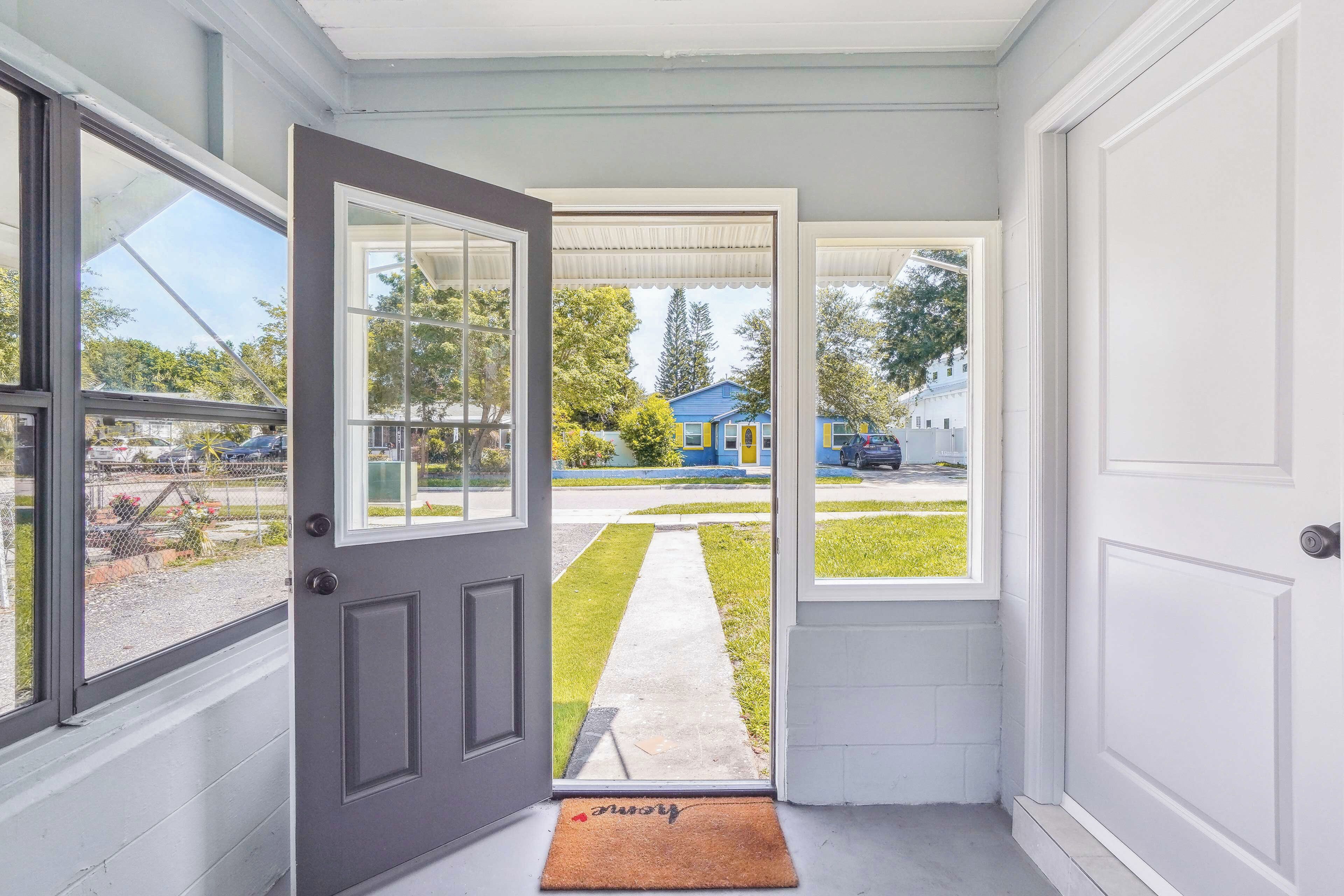 A doorway leading to a residential driveway with a blue house in the background.