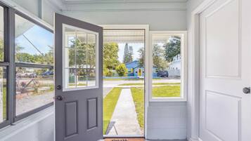 A doorway leading to a residential driveway with a blue house in the background.