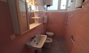 A compact bathroom with a sink, toilet, and shower.