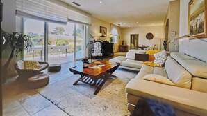 Amplia sala de estar con un gran ventanal corredizo que da a un espacio al aire libre, un sofá, una mesa de centro y una silla.