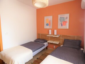 Una habitación con dos camas individuales, un cabecero de madera y dos lámparas de pared.