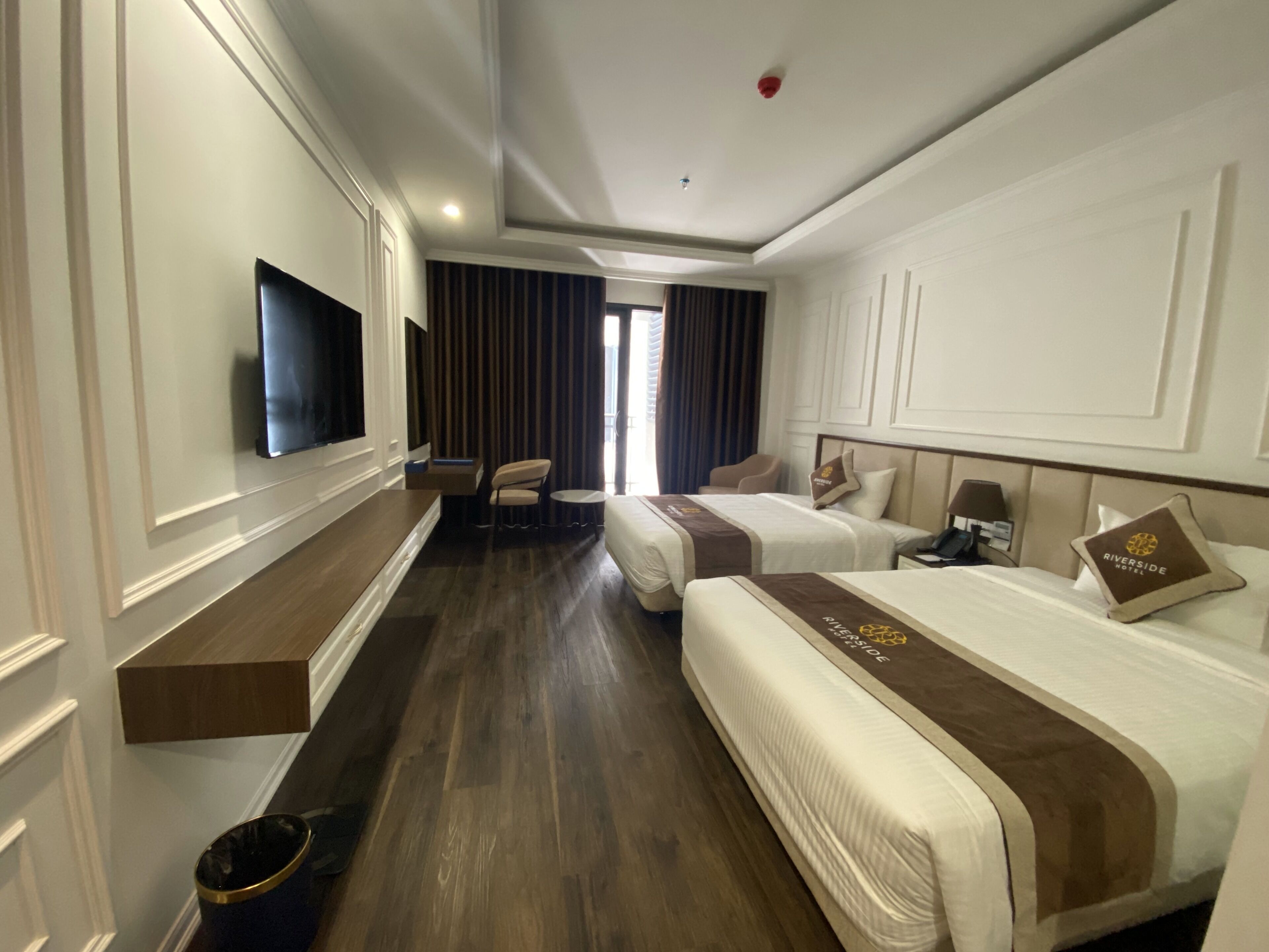 A hotel room with two beds, a TV, a desk, and a chair.