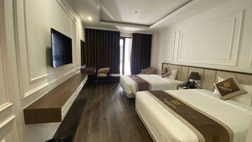 A hotel room with two beds, a TV, a desk, and a chair.