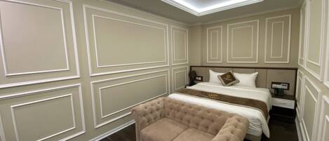 A hotel room with a large bed, a sofa, a round table, and a nightstand.