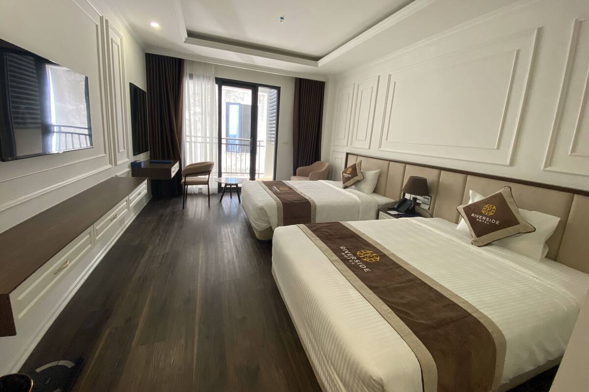 Una habitación de hotel con dos camas, un escritorio, una silla y un televisor.