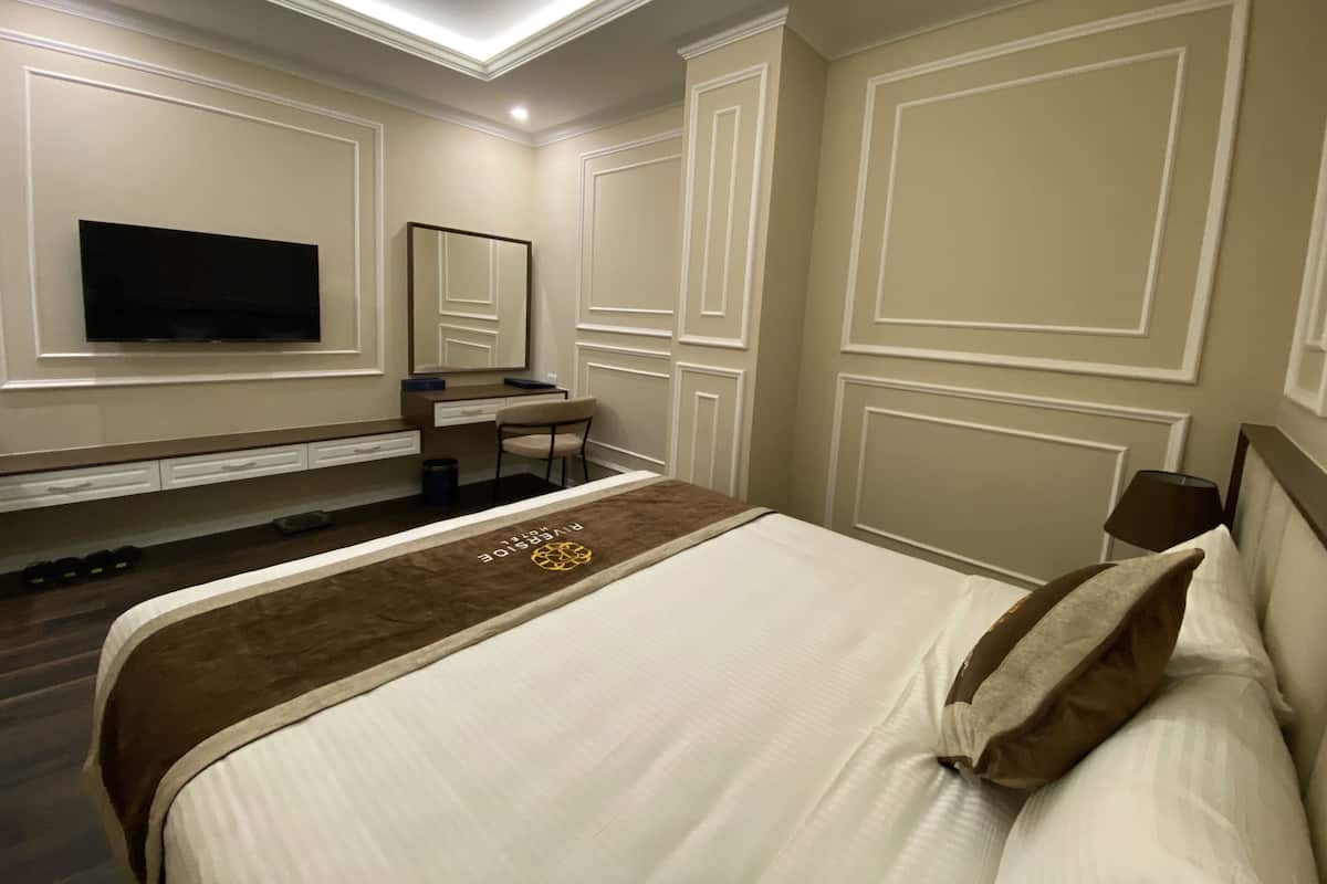 Una habitación de hotel con una cama, un escritorio, una silla, un televisor y un espejo.