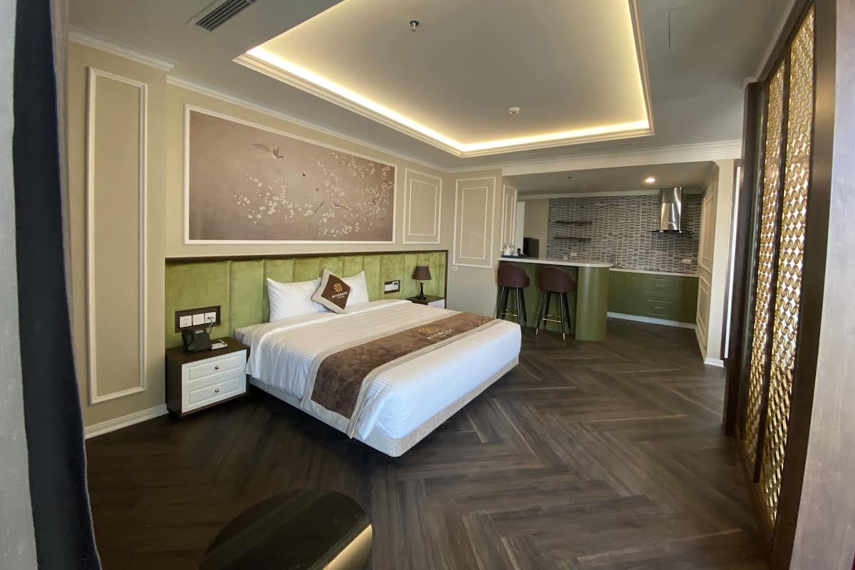 Una habitación de hotel moderna con una cama grande, una kitchenette pequeña y un comedor.