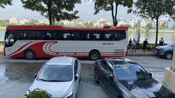 Un autobús rojo y blanco estacionado cerca de un cuerpo de agua, con una fila de coches adelante.