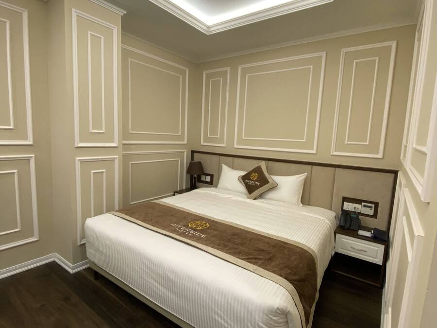A hotel room with a large bed, a nightstand, a lamp, and a ceiling light.