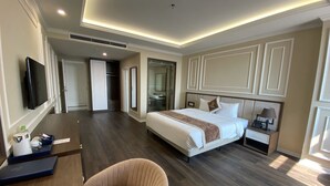 A hotel room with a large bed, bedside table, lamp, and a chair. There is a TV mounted on the wall and a door leading to a bathroom. - Riverside Hotel Ha Nam (Phu Ly)