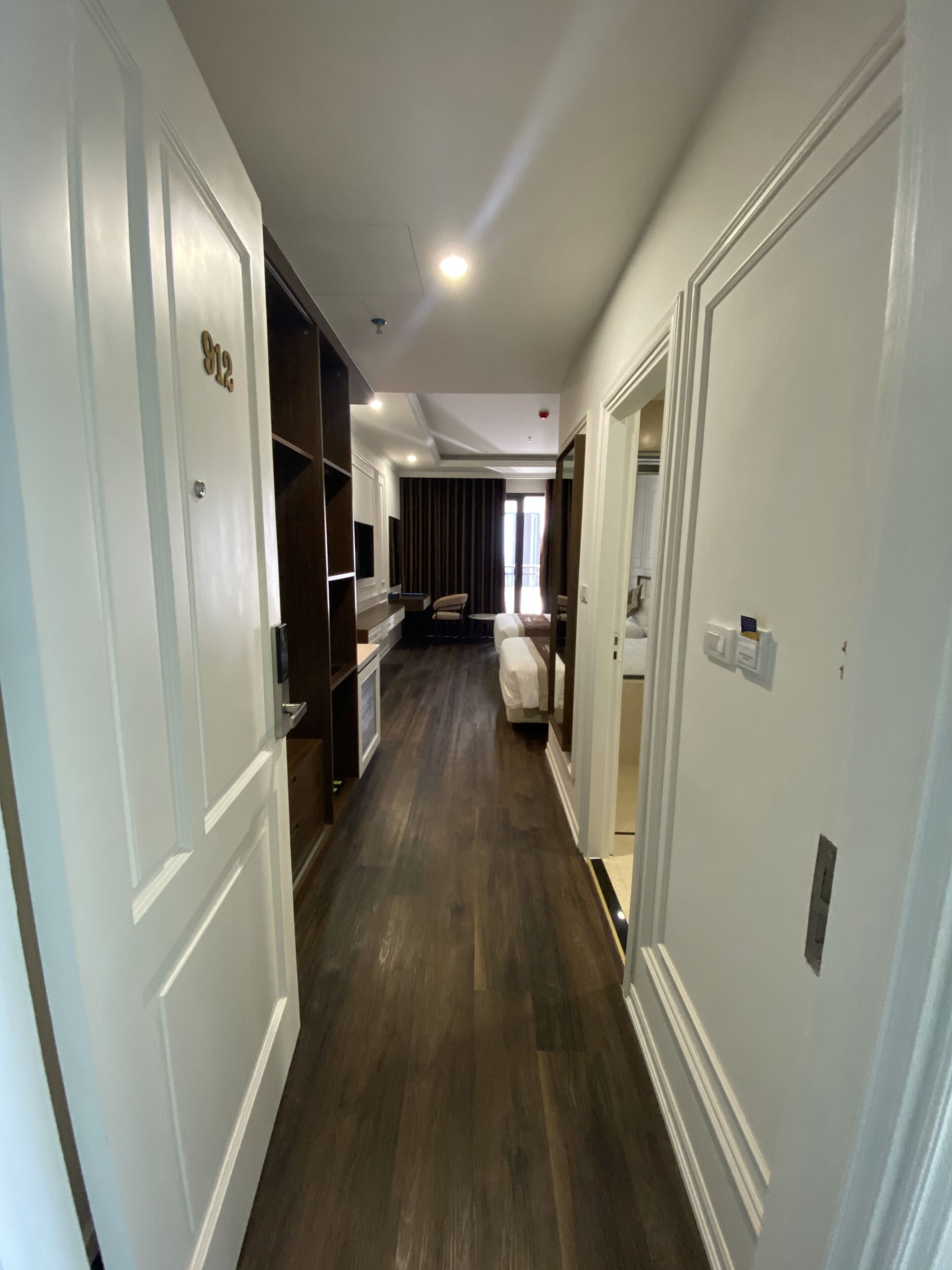 A hallway with wooden flooring, white walls, and doors on both sides.