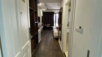 A hallway with wooden flooring, white walls, and doors on both sides.