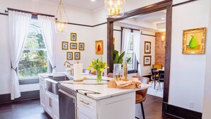 A modern kitchen with a central island, white cabinetry, and a dining area with a wooden table and chairs.