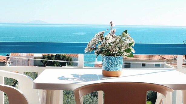 A balcony with a table and chairs, overlooking a coastal view with a clear sky. - Seaview - Selfcatering Apartment - Helen No 1 (North Kynouria)