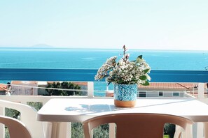 A balcony with a table and chairs, overlooking a coastal view with a clear sky. - Seaview - Selfcatering Apartment - Helen No 1 (North Kynouria)