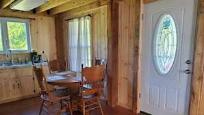 Un interno in legno con un tavolo da pranzo, sedie, angolo cottura e una porta con una finestra a vetri colorati.