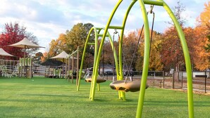 A playground with swings and a fenced area. - Quiet, 4-bed home with a park view. (Clarksville)