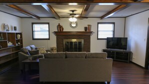 A living room with a fireplace, a sofa, a television, and a bookshelf. - Quiet, 4-bed home with a park view. (Clarksville)
