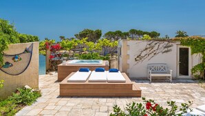 Un espace aménagé au bord de la piscine, avec des chaises longues, un jacuzzi et un banc.