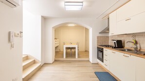 Une cuisine moderne avec des meubles blancs, une cuisinière à gaz et un coin repas comprenant une table et des chaises.