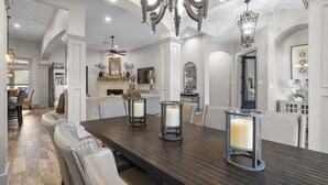 Un comedor amplio con una mesa larga, múltiples sillas y candelabros decorativos.