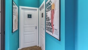 A hallway with teal walls, a white door, and framed posters. - Gravina8 (Naples)