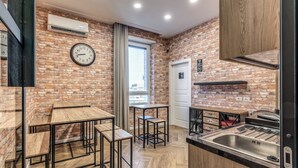 A kitchen with a brick wall, wooden tables, a sink, and a window with a view. - Gravina8 (Naples)