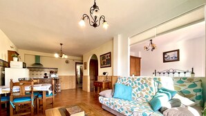 Un salon spacieux avec un canapé à motifs, des meubles en bois et un sol carrelé.