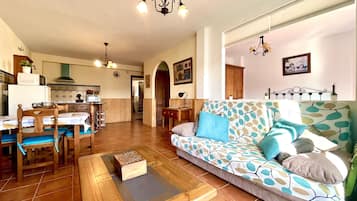 Un salón amplio con un sofá estampado, muebles de madera y suelo de baldosas.