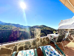 Un balcon avec un mur en pierre, une table sur laquelle est posée une plante en pot et une chaise.