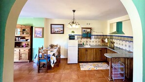 Une cuisine avec coin repas, dotée d’un plan de travail en carreaux, de meubles en bois et d’un îlot central.