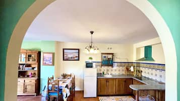Una cucina con zona pranzo, caratterizzata da piastrelle a parete, mobili in legno e un'isola centrale.