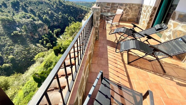 Un balcon offrant une vue sur un paysage montagneux et la mer.