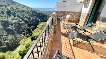 Un balcón con vistas a un paisaje montañoso y al mar.