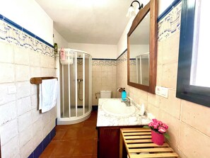 Une salle de bain équipée d’une douche, d’un lavabo, d’un miroir et de toilettes.