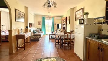 Una sala de estar acogedora con sofá, mesa de comedor y sillas, una cocina con refrigerador y microondas, y un comedor con vistas al exterior.