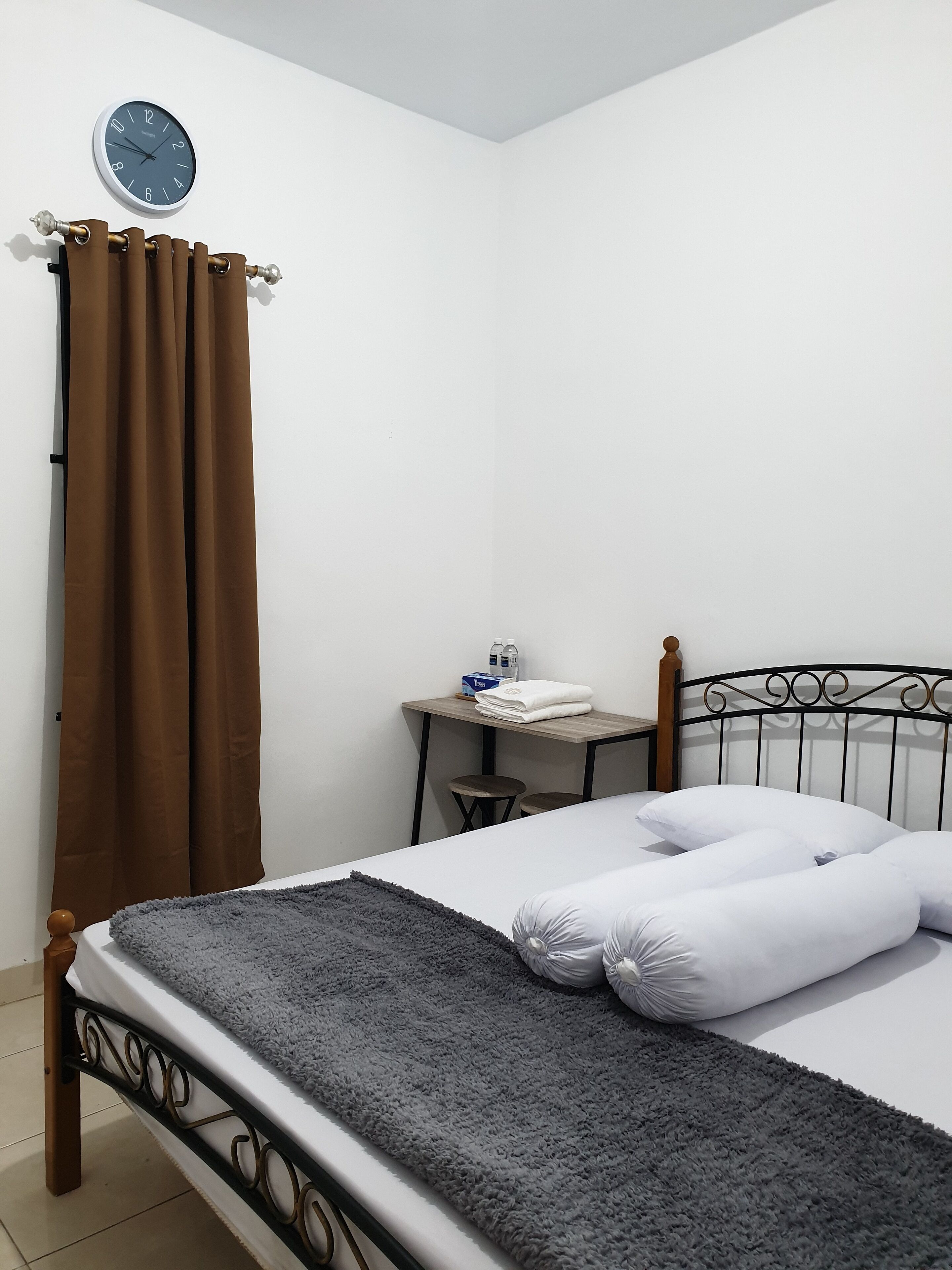 Une chambre bien rangée, avec un lit, un bureau et une horloge au mur.