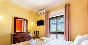 Ein Hotelzimmer mit Bett, Schminktisch, Fernseher und einem Fenster mit Vorhängen.