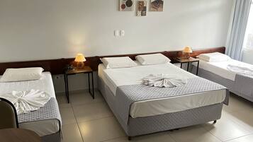 A hotel room with two beds, a desk, a chair, and a lamp.
